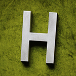 letter H in metal on green velvet